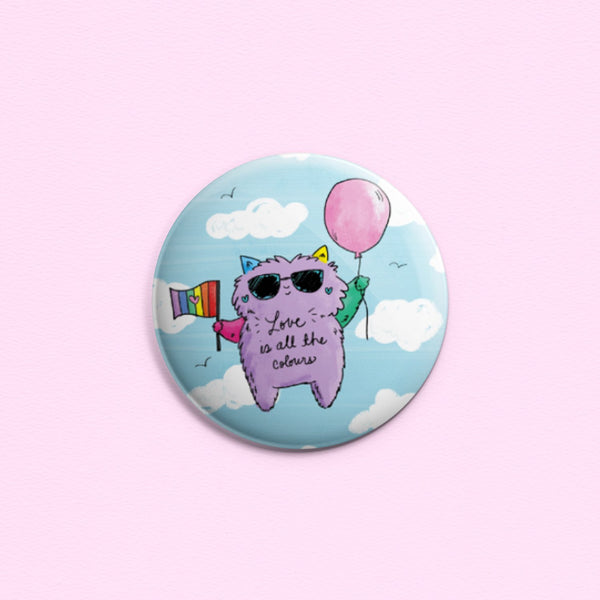 Love Is All The Colours - Button or magnet with an illustration of a cool cat holding a balloon in one hand and a pride flag in the other, floating in the sky.